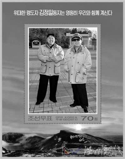 30日，朝鮮發(fā)行紀(jì)念金正日的郵票小型張2枚。其中一枚郵票的中央是金正日與金正恩在一起的照片，上端寫著“偉大領(lǐng)導(dǎo)者金正日同志永遠(yuǎn)和我們在一起”。 新華社發(fā)